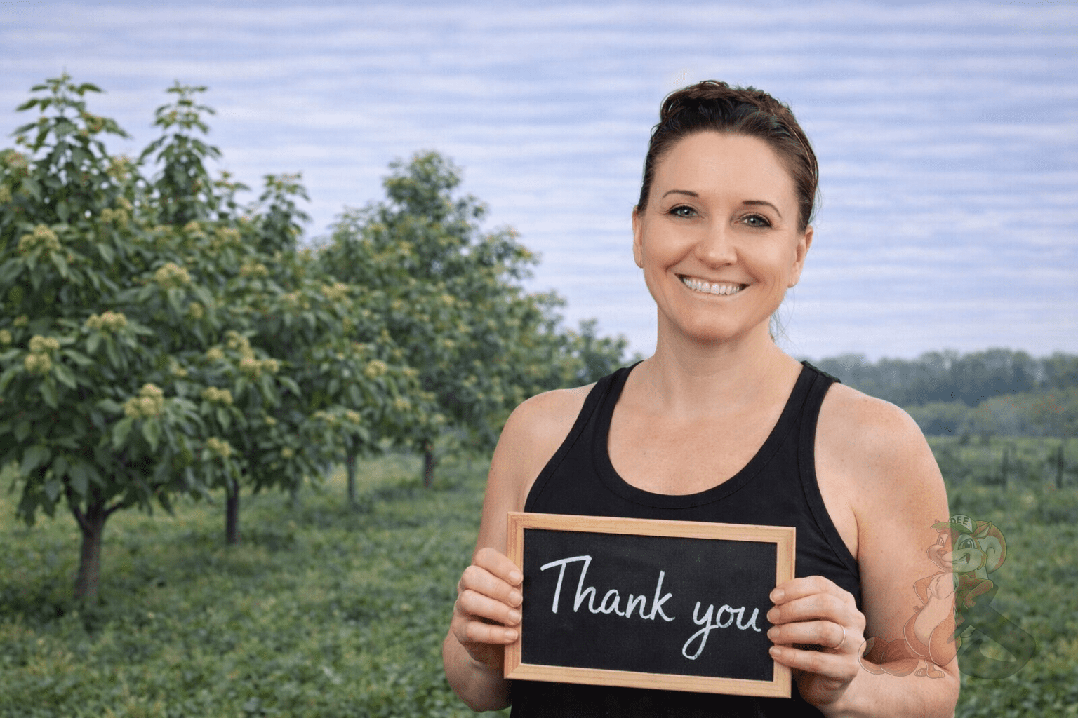 Heather from Nuts About Dee’s Berries holding a thank you sign in the orchard honoring our Nuts About Dee’s Berries Supporters