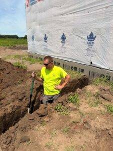 Sean Brown of Piping Pro Plumbing digging the trench for the orchard irrigation mainline near the farm building at Nuts About Dee's Berries.