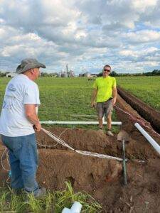 Crew installing irrigation risers and control wire connections for orchard crop blocks at Nuts About Dee's Berries.