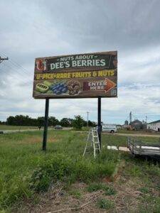 Nuts About Dee's Berries billboard sign along Highway 104 in Brodhead Wisconsin promoting U-pick rare fruits and nuts including pawpaw, chestnuts, and berries.