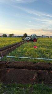 Tractor backfilling trenches after installation of the orchard irrigation mainline at Nuts About Dee's Berries.