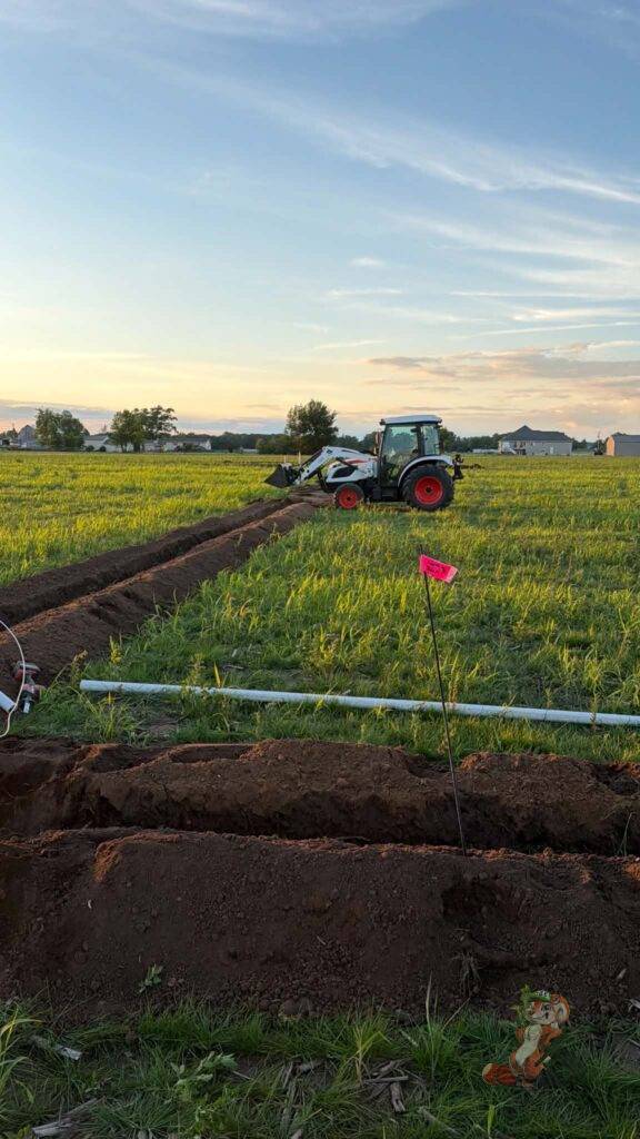 Tractor backfilling trenches after installation of the orchard irrigation mainline at Nuts About Dee's Berries.