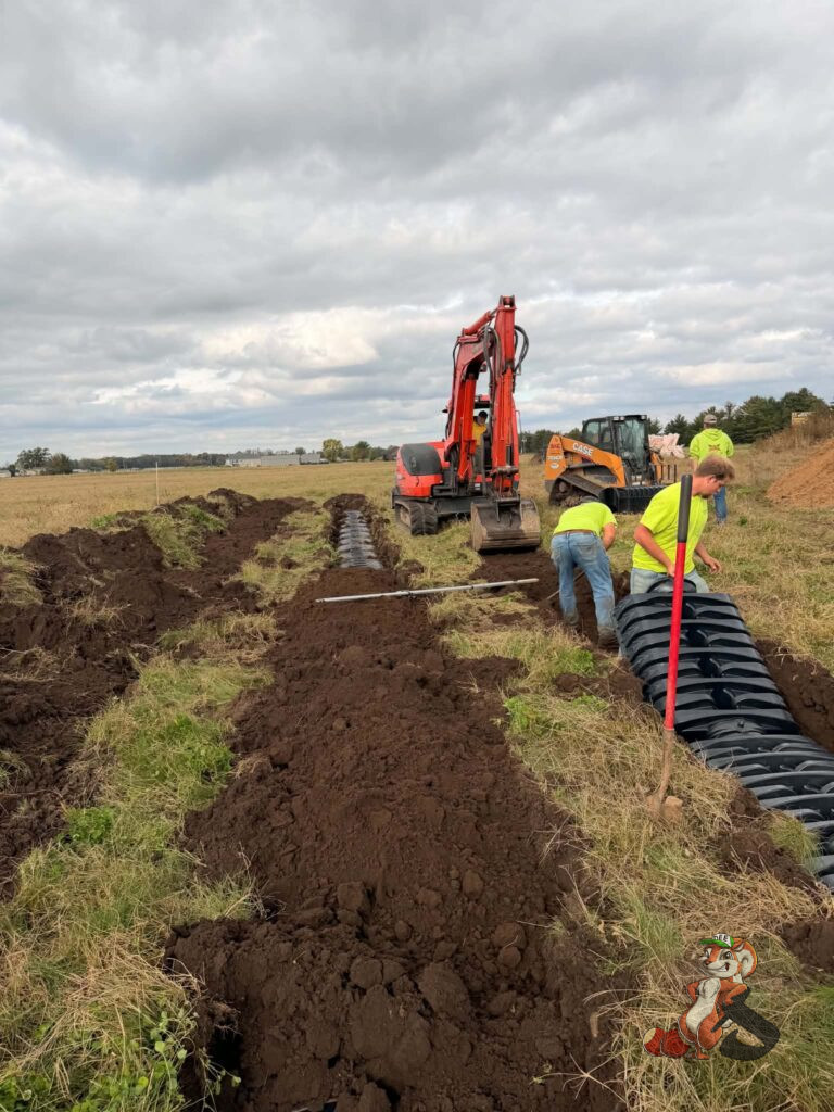 Farm septic installation underway with excavator, drainage chambers, and construction crew at Nuts About Dee's Berries in Brodhead, Wisconsin.
