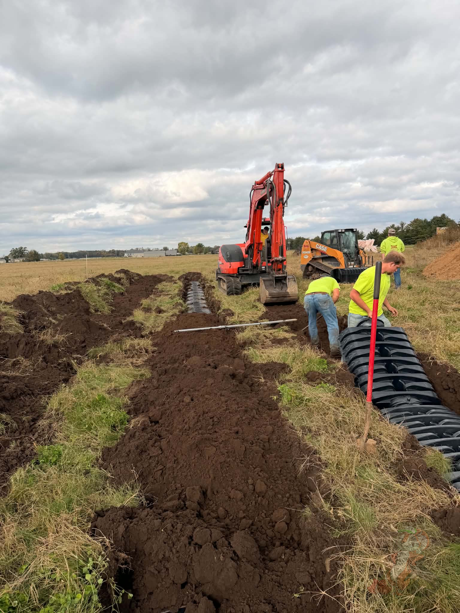 Farm septic installation underway with excavator, drainage chambers, and construction crew at Nuts About Dee's Berries in Brodhead, Wisconsin.